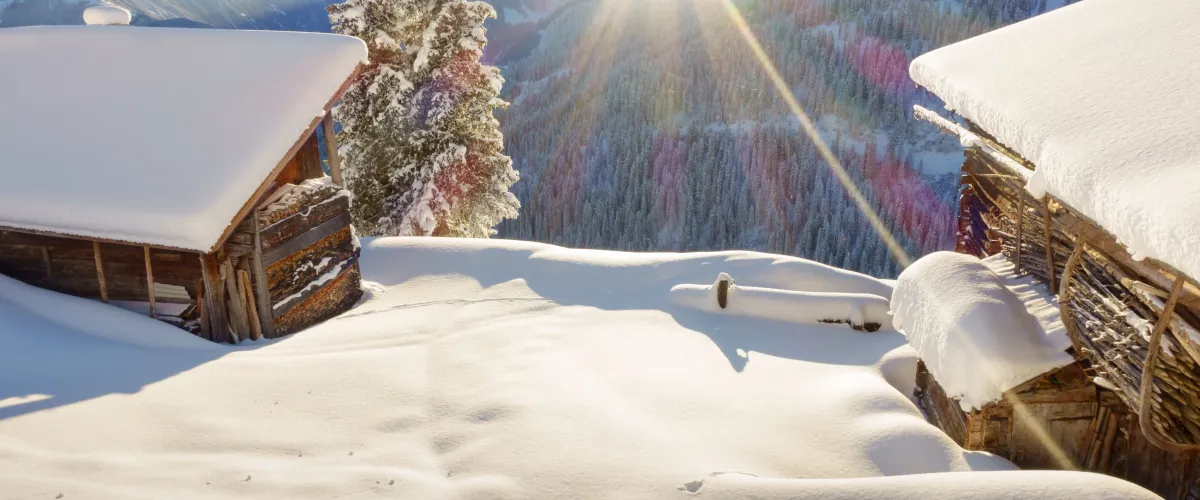 Skivakantie in Oostenrijk met een besneeuwde almhut en bergpanorama in de Alpen