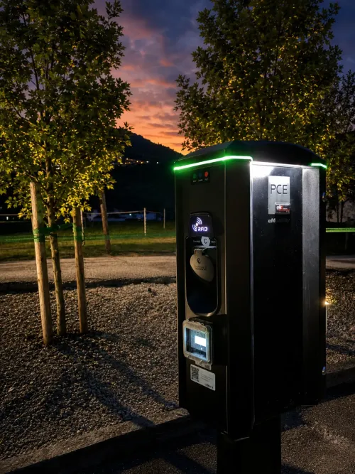 Moderne PCE eMobility E-Ladestation direkt am Parkplatz des Hotels Alpenhof in Zell am Ziller bei Dämmerung.