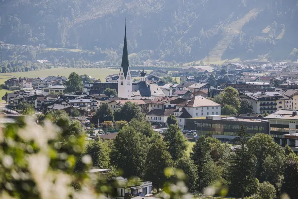 Blick auf den idyllischen Urlaubsort Zell am Ziller im Herzen des Zillertals mit der markanten Pfarrkirche vor der Tiroler Alpenkulisse.